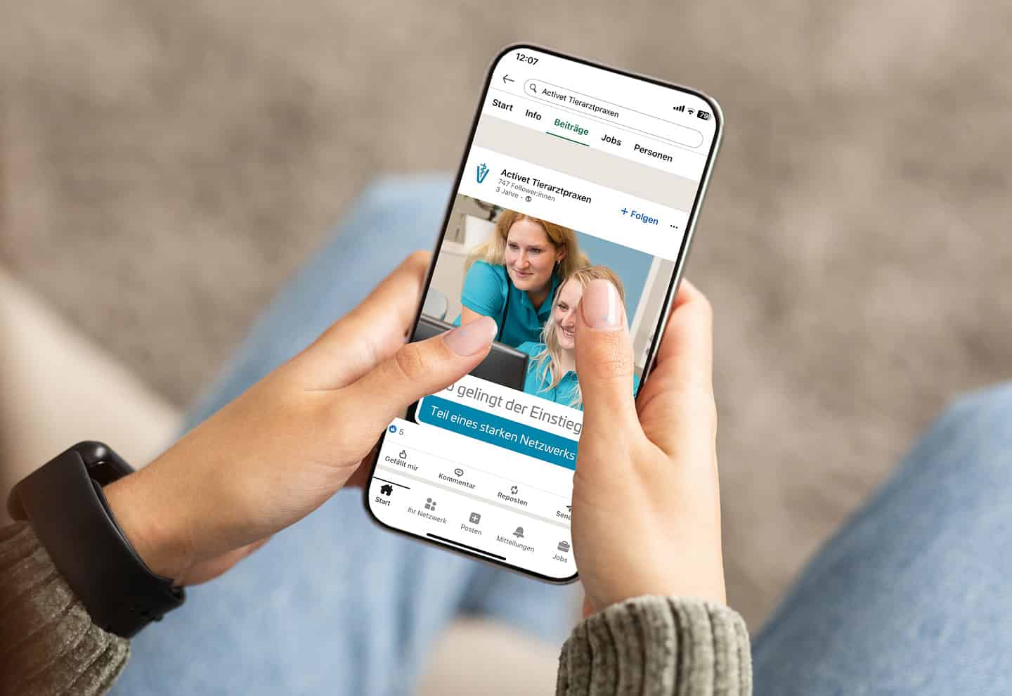 Smartphone mit LinkedIn-Beitrag der Activet Tierarztpraxen in den Händen einer Person.